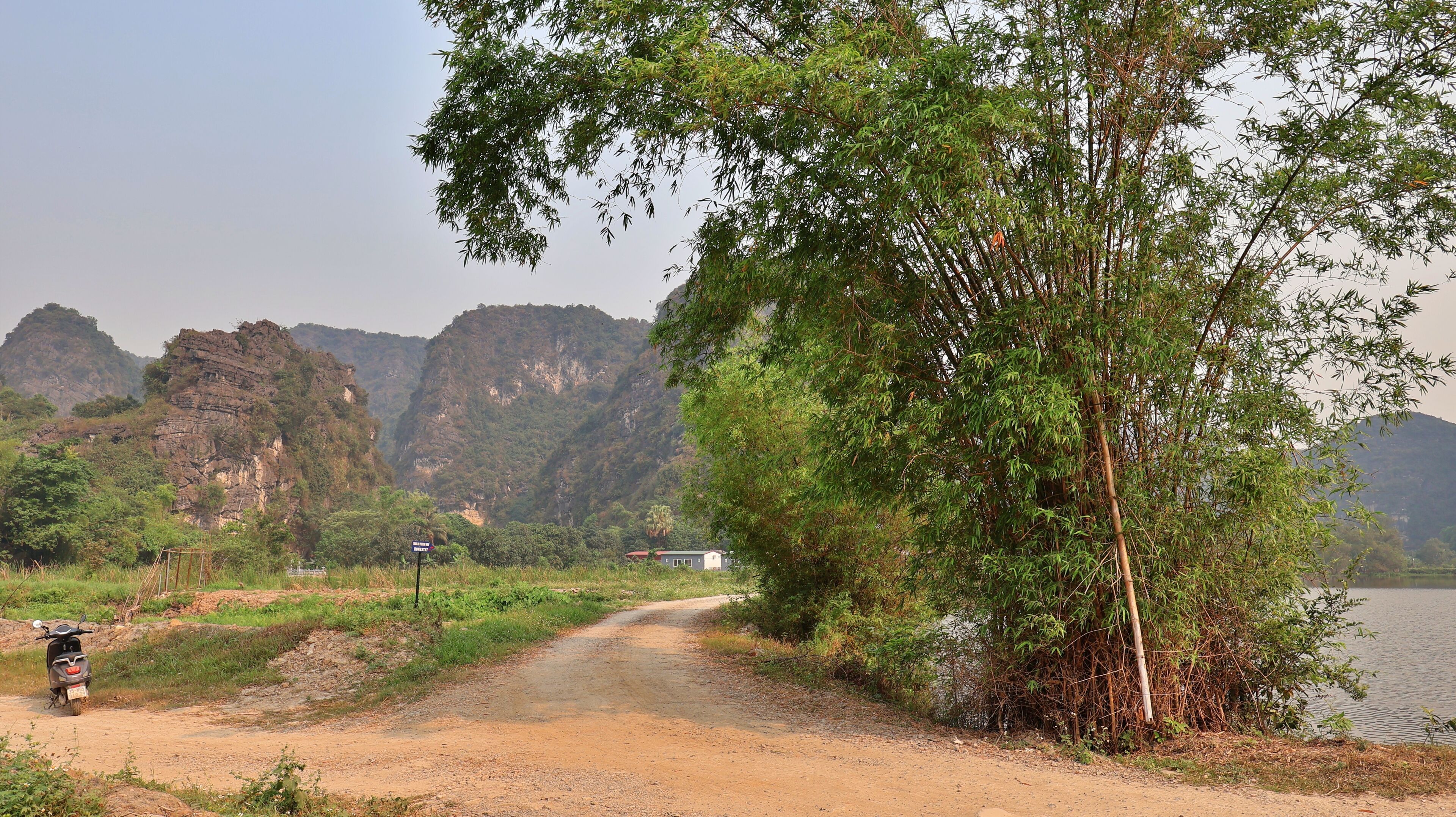 A dirt path leading to a building with a view of rocky cliffs and a body of water.