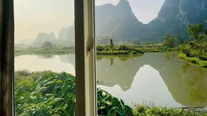 Vista a través de una ventana que muestra un paisaje natural con una masa de agua tranquila, vegetación y montañas distantes.
