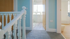 A staircase with white balusters leading to a room with light blue walls and a visible window. - Gorgeous, fully refurbished centrally located cosy cottage (Hawick)