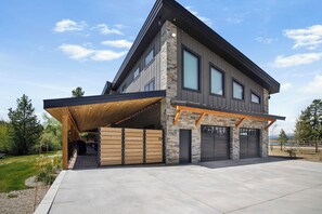 Une maison moderne à deux étages, dotée d’un garage fermé, d’une façade en pierre et de grandes fenêtres.
