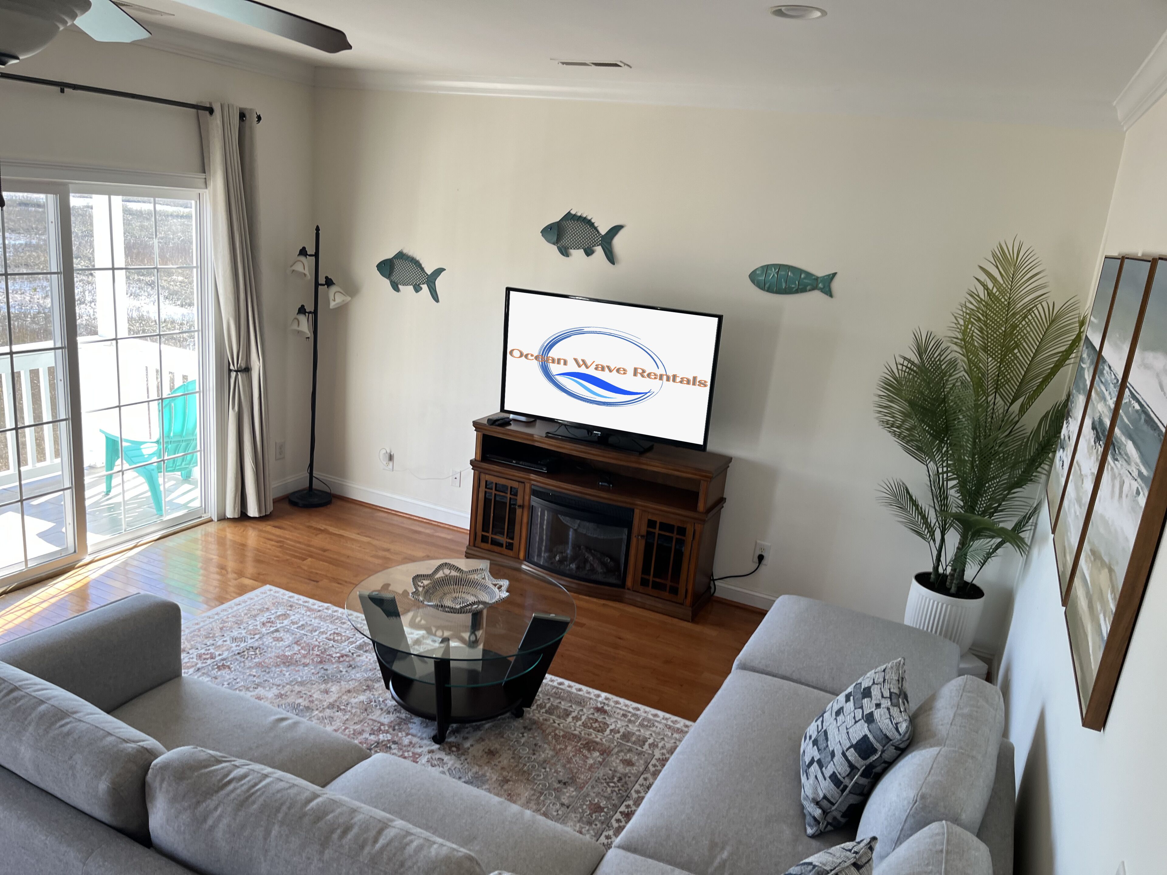 Una sala de estar con un sofá, una mesa de centro, una televisión y decoración de peces en la pared.