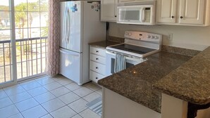 Cozinha com armários brancos, micro-ondas, fogão e ventilador de teto.