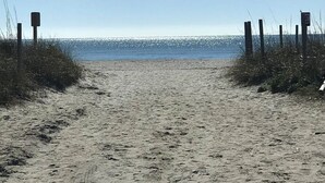 Um caminho de areia que leva ao mar, com estacas de madeira em ambos os lados.