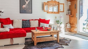 A cozy living room with a red sofa, wooden coffee table, and a framed deer picture. - Nice apartment for 4 guests with WIFI, TV and balcony (Basse-nendaz)