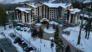 Un hotel de varios pisos con un telesilla, rodeado de montañas nevadas.