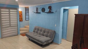 A living room with a grey sofa, a wooden cabinet, and a staircase leading to another room. - Comfortable & Beautiful house in Caucel (Merida)