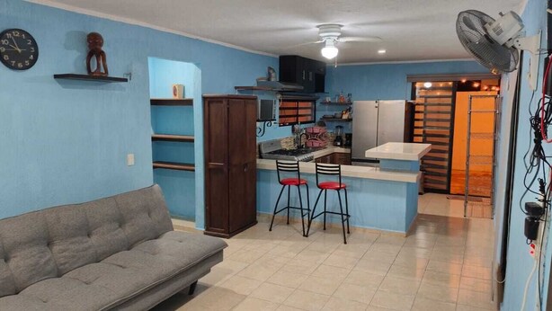 A compact living space with a kitchenette, a sofa, and a dining area with stools. - Comfortable & Beautiful house in Caucel (Merida)