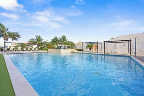 Piscina com espreguiçadeiras e palmeiras.