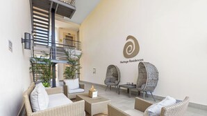 Een moderne lounge met rieten meubels, een trap en een bord met daarop Heritage Residences.