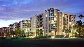 A multi-story hotel with balconies, a street view, and a clear sky.