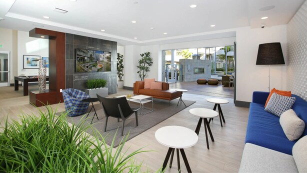 A modern hotel lobby with a seating area, a fireplace, and a large window providing a view of the outside.