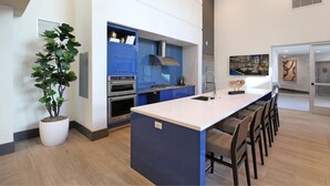 A modern kitchen with blue cabinets, a central island, and a potted plant.