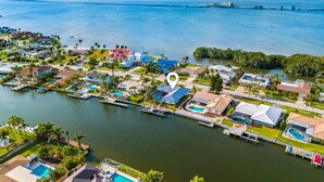 An aerial view of a coastal residential area with houses, a marina, and a large body of water. - Canal Access: Boat Lift, Heated Pool & Dock (Cocoa Beach)