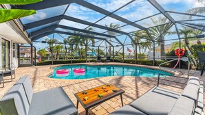 A pool area with lounge chairs, a table, and a covered patio. - Canal Access: Boat Lift, Heated Pool & Dock (Cocoa Beach)