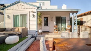 Et moderne hus med en patio, møbleret med sofa, træbord og en lille have.