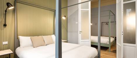 A bedroom with a canopy bed, a bedside table, a lamp, and a wardrobe.