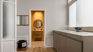 A modern bathroom with a wooden vanity, a round mirror, and a small sink. - Constance Luxury Apartment by DomuSicily (Palermo)