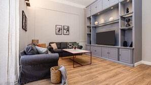 A modern living room with a grey sofa, a coffee table, and a TV on a built-in shelf. - Constance Luxury Apartment by DomuSicily (Palermo)