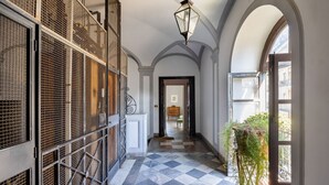 A hallway with a checkered floor, metal gates, and a hanging plant. - Palazzo Fatta Apartment by DomuSicily (Palermo)