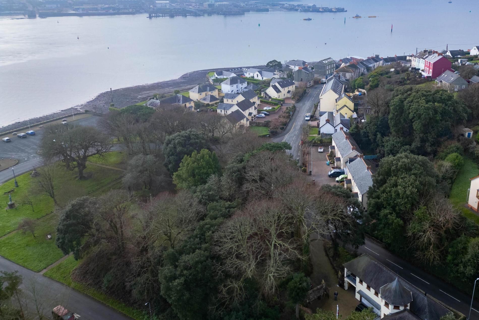 Luchtbeeld van een kustgebied met huizen, een weg en een wateroppervlak.