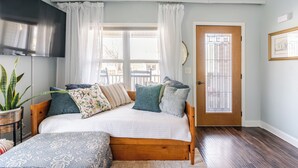 Une chambre à coucher avec un lit en bois, des rideaux blancs, une plante en pot et une porte avec une fenêtre.