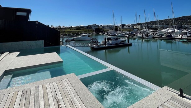 Un port de plaisance avec des bateaux amarrés, une piscine et une terrasse en bois.