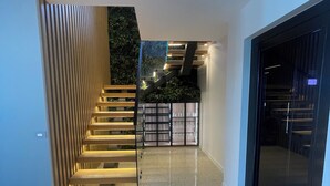 Un intérieur moderne avec un escalier menant à un balcon, une porte vitrée et un plancher poli.
