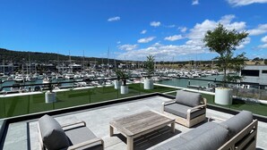 Une terrasse dotée de mobilier d’extérieur et offrant une vue sur le port de plaisance.