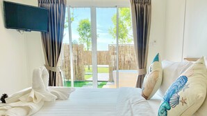 A hotel room with a bed, a TV mounted on the wall, and a view of the outside through a glass door. - Charome Resort (Khlong Yai)