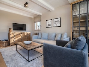 Ein modernes Wohnzimmer mit einer Couch, einem Couchtisch, einem Holzschrank und einem Fernseher.