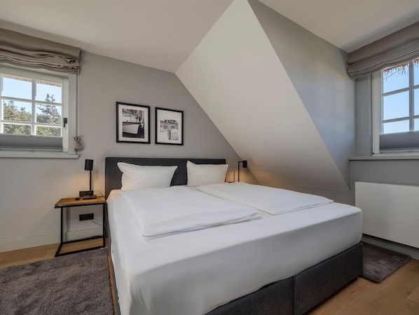 Ein modernes Schlafzimmer mit einem großen Bett, zwei Nachttischen und einer geneigten Decke.