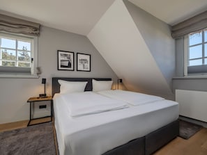 Un dormitorio moderno con una cama grande, dos mesitas de noche y un techo inclinado.