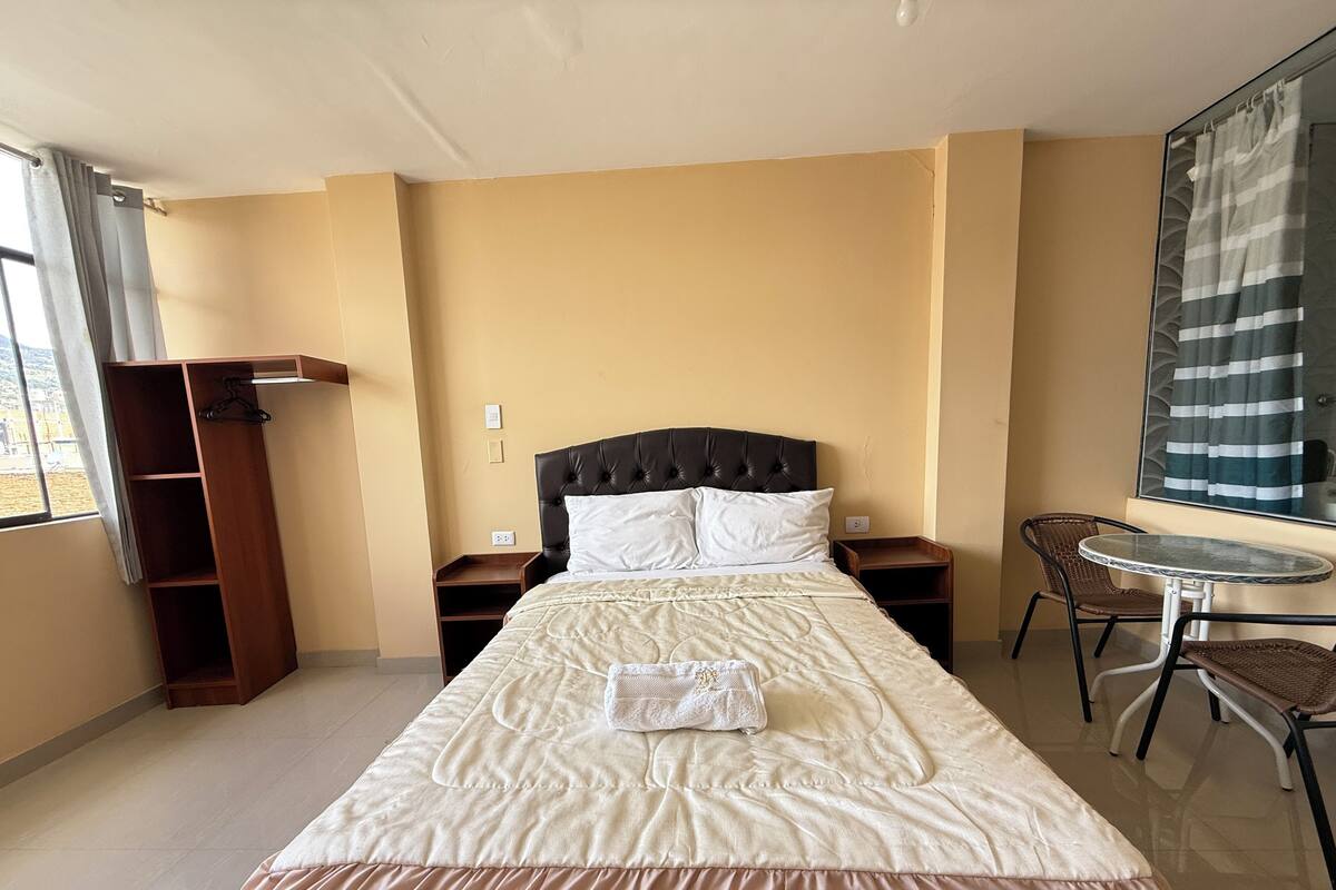Ein Hotelzimmer mit Bett, Kleiderschrank, kleinem Tisch und Stuhl.