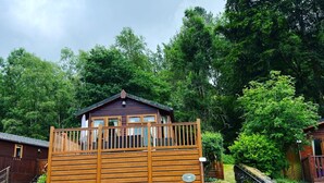 Une cabane en bois dotée d’un balcon, entourée d’une forêt dense.