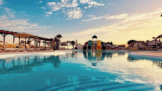 A swimming pool with lounge chairs and a water slide.