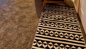Un salon chaleureux avec deux canapés en cuir noir, un tapis à motifs et des miroirs décoratifs accrochés au mur.