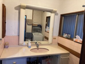 A bathroom with a sink, mirror, and toiletries.