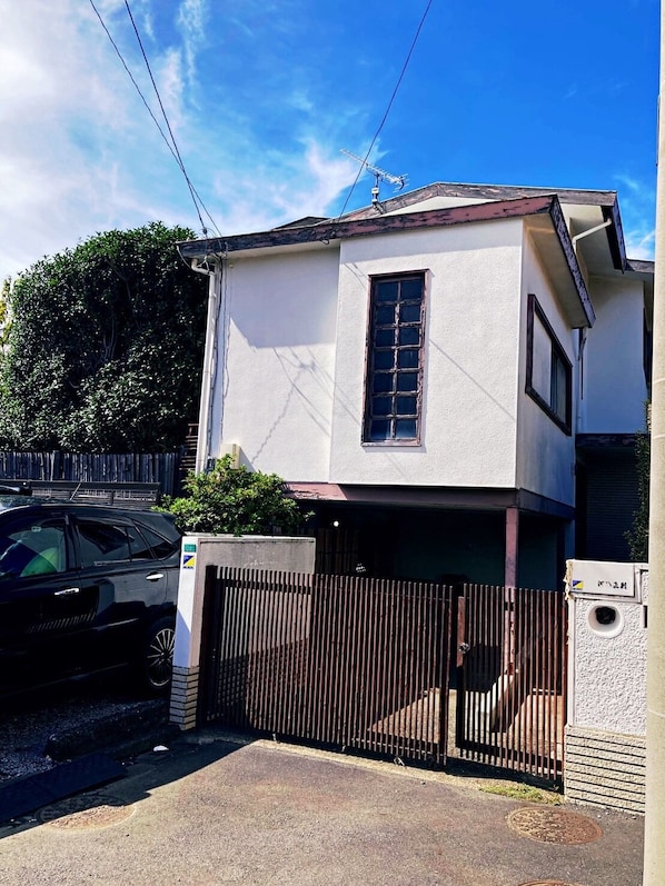 A two-story building with a gated entrance and a parked car.