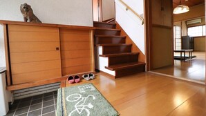 Un escalier menant à une pièce dotée d’une porte coulissante, une paire de chaussures et un tapis orné d’un symbole de vélo.