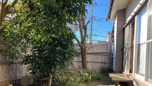 Un jardin avec une terrasse en bois, un arbre et un chemin de gravier.