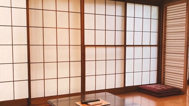 Une pièce de style japonais traditionnel, avec un sol recouvert de tatamis, une table basse et des paravents en papier de riz (shoji).