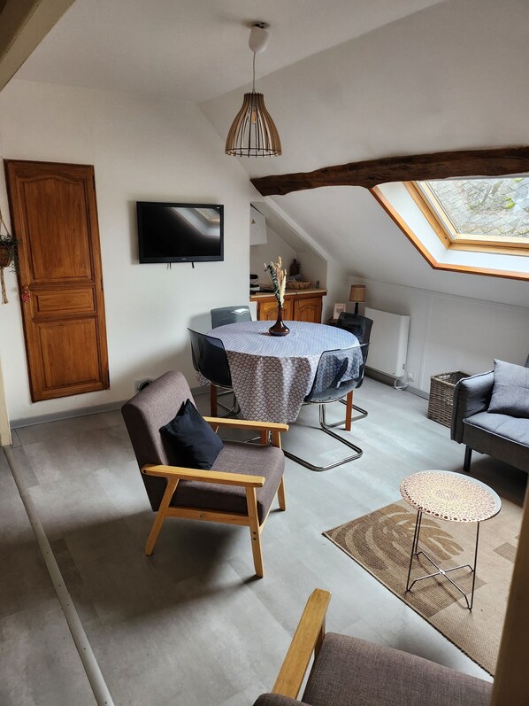 A cozy loft-style room with a dining table, a sofa, and a small side table.