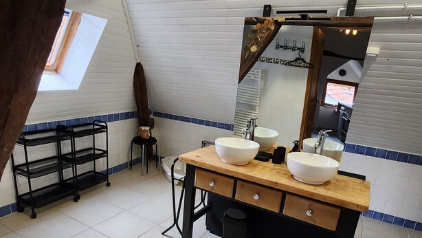 A bathroom with a wooden vanity, two sinks, a mirror, and a skylight. - 3-bedroom apartment, 2 steps from Chambord, Loire castles, Beauval (Tour-en-Sologne)
