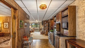 A wooden interior with a sofa, a dining table, and a bookshelf. - Lakefront Lodge-Private Dock-Swimming-Game Room (Crivets)