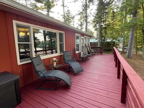 A covered outdoor deck with red flooring and multiple seating areas. - Lakefront Lodge-Private Dock-Swimming-Game Room (Crivets)