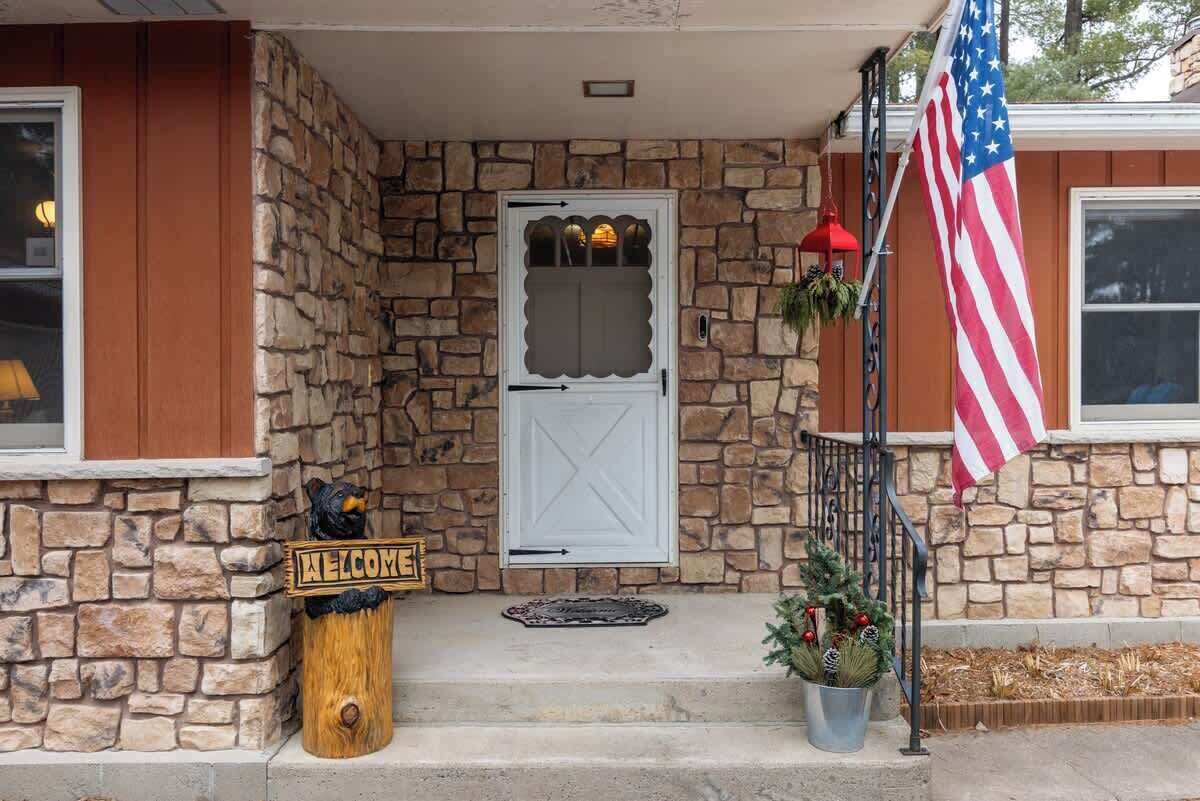 Une maison en pierre avec une porte blanche, une pancarte d’accueil et un drapeau américain.