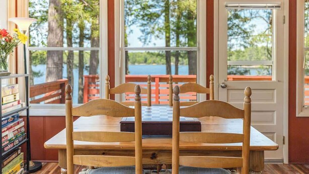 A wooden table with chairs in a room with large windows overlooking a body of water. - Lakefront Lodge-Private Dock-Swimming-Game Room (Crivets)