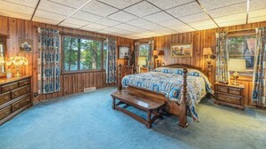 A bedroom with a wooden floor, a four-poster bed, a nightstand, a dresser, and a window with curtains. - Lakefront Lodge-Private Dock-Swimming-Game Room (Crivets)