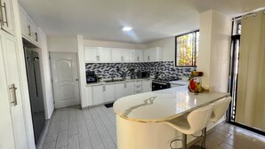 A modern kitchen with white cabinets, a central island, and a patterned backsplash. - 4-bedroom house in the middle of superb Sosúa with WiFi, AC (Sosúa)