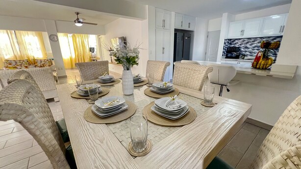 A modern dining area with a long table set for a meal, surrounded by comfortable chairs. - 4-bedroom house in the middle of superb Sosúa with WiFi, AC (Sosúa)